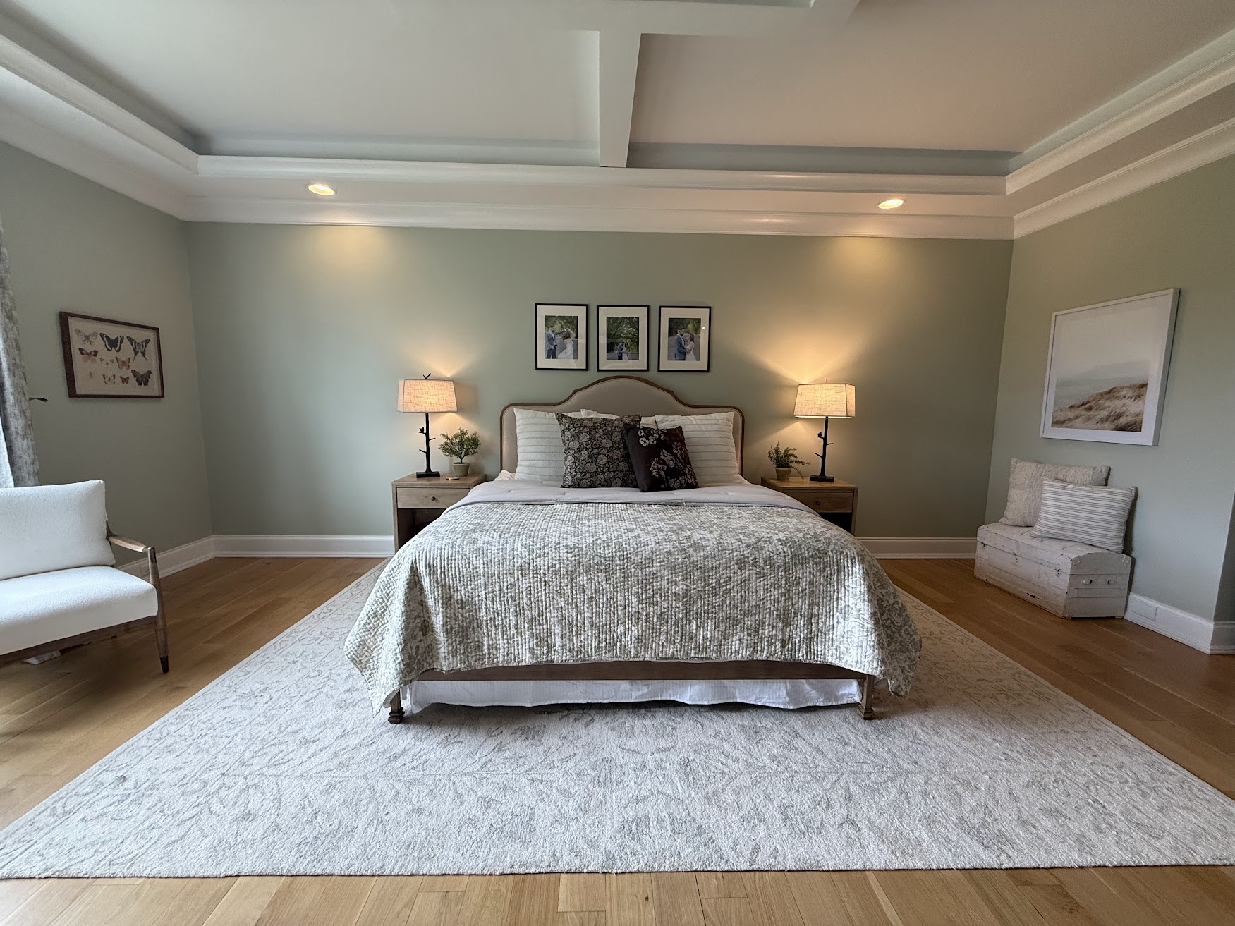 A beautifully staged master bedroom with sage green walls and soft neutral linens